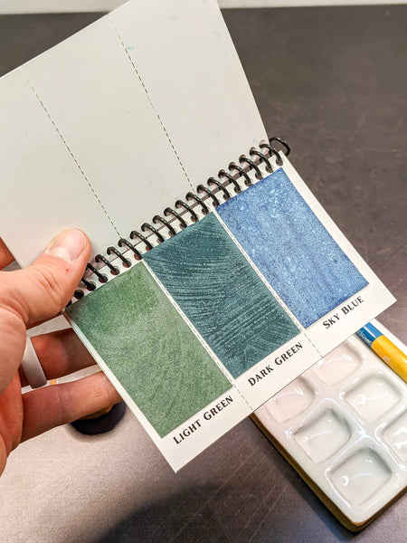 Peerless Watercolors Mini Complete Edition set with six watercolor sheets and vibrant paint swatches displayed on a white background.