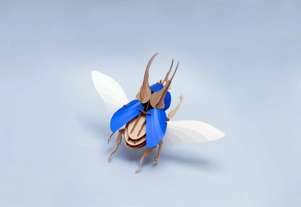 Blue scaled Paper Atlas Beetle craft by Assembli showing detailed wings and textured body on a white background.