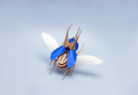 Blue scaled Paper Atlas Beetle craft by Assembli showing detailed wings and textured body on a white background.