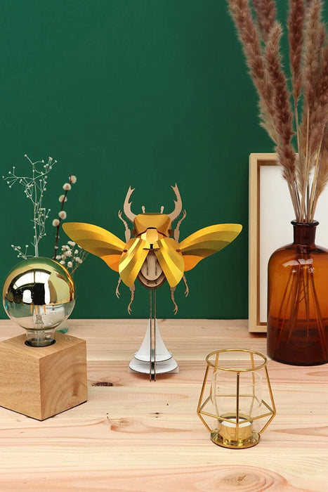 Large paper stag beetle craft by Assembli, featuring detailed gold-colored paper wings and body for creative arts projects.