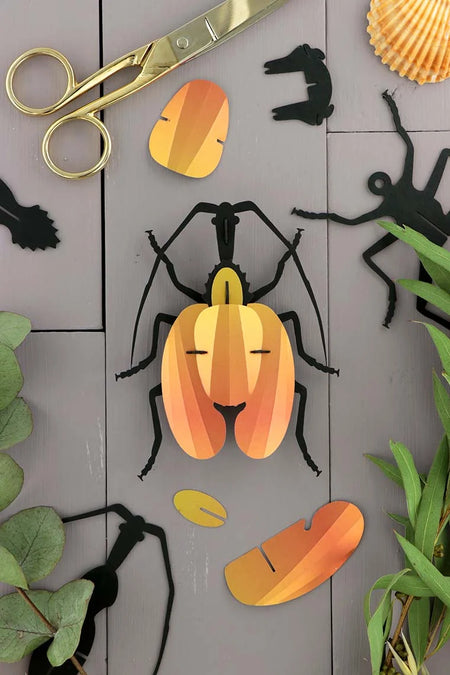 Yellow paper violin craft by Assembli featuring detailed paper folding and vibrant colors, perfect for creative arts projects.