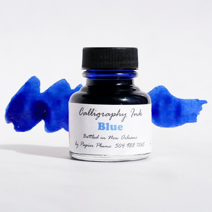 Bottle of Papier Plume blue calligraphy ink showing the ink inside and the label on the glass bottle.