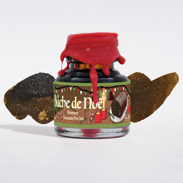 Papier Plume Bûche de Noël shimmer fountain pen ink in a glass bottle, featuring festive holiday-themed packaging.