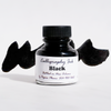 Black bottled calligraphy ink by Papier Plume in a clear glass bottle with black ink inside.