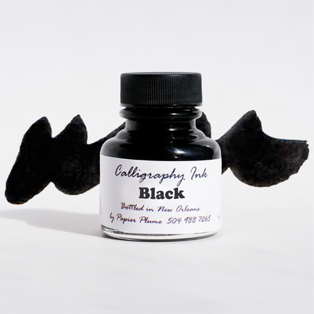 Black bottled calligraphy ink by Papier Plume in a clear glass bottle with black ink inside.