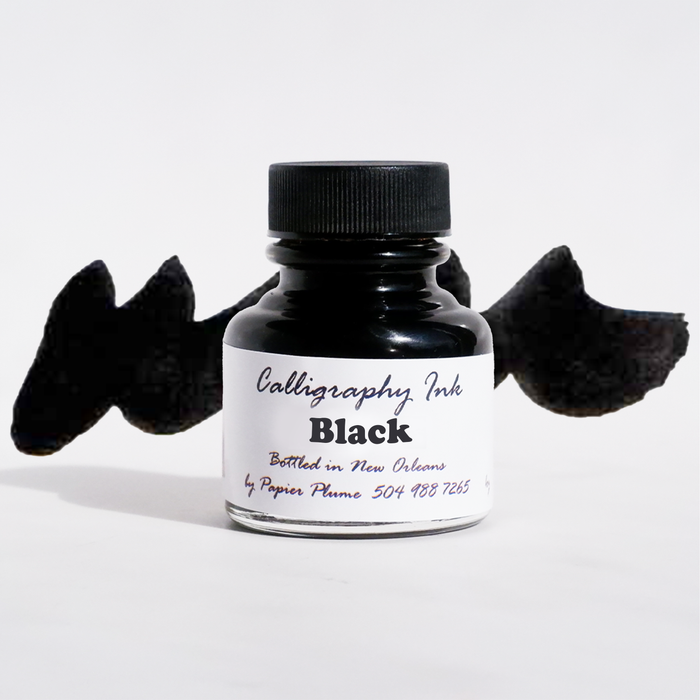 Black bottled calligraphy ink by Papier Plume in a clear glass bottle with black ink inside.