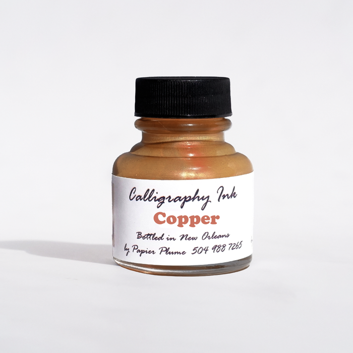 Bottled Papier Plume metallic copper calligraphy ink in a glass bottle, showcasing shiny copper ink for artistic writing projects.