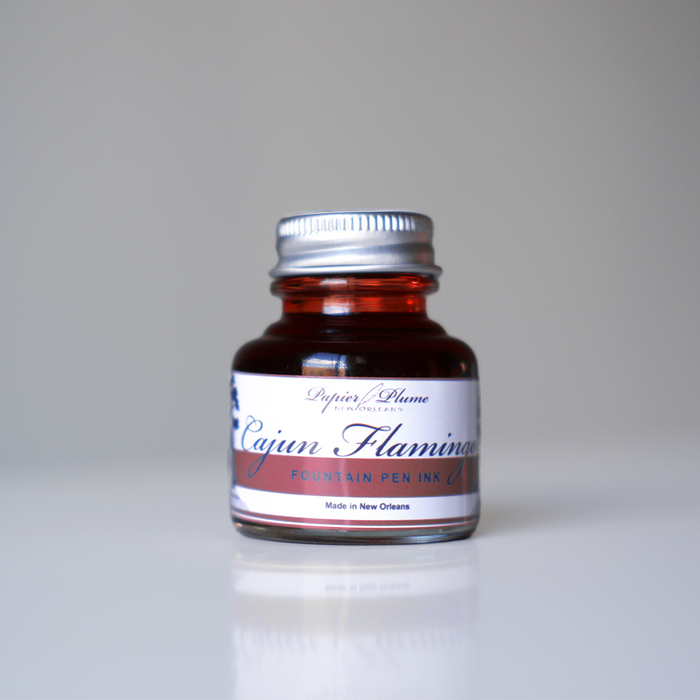 Papier Plume Cajun Flamingo fountain pen ink in a 30ml bottle with vibrant pink-orange ink inside.