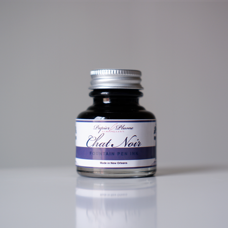Papier Plume Chat Noir fountain pen ink bottle with black ink in a glass container, designed for elegant writing.