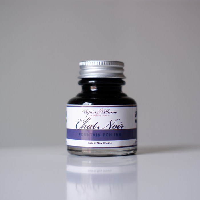 Papier Plume Chat Noir fountain pen ink bottle with black ink in a glass container, designed for elegant writing.