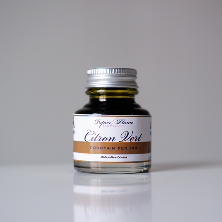 Papier Plume fountain pen ink in vibrant citron vert green, shown in a glass bottle with a black cap.