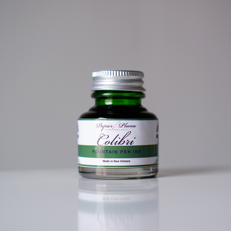 Papier Plume Colibri fountain pen ink bottle with vibrant blue ink in a clear glass container.