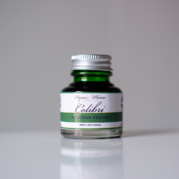 Papier Plume Colibri fountain pen ink bottle with vibrant blue ink in a clear glass container.