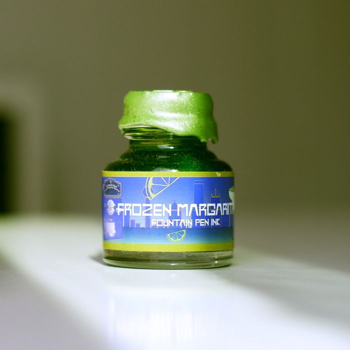 Papier Plume Frozen Margarita shimmer fountain pen ink in a bottle, showcasing vibrant blue and gold accents suitable for writing.