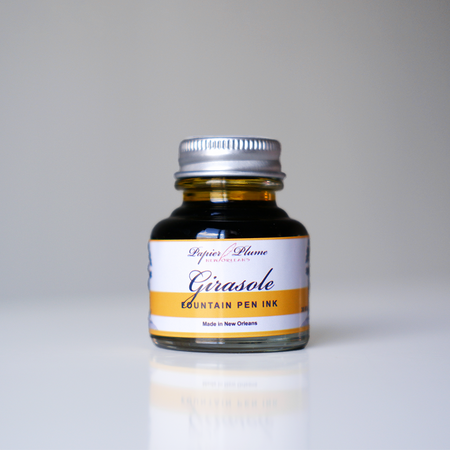 Papier Plume Girasole fountain pen ink in a 30ml bottle with vibrant yellow-orange ink visible in the bottle.