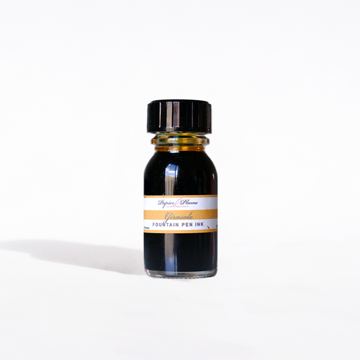 Papier Plume Girasole fountain pen ink bottle, 15ml with vibrant yellow-orange ink visible in the clear glass container.