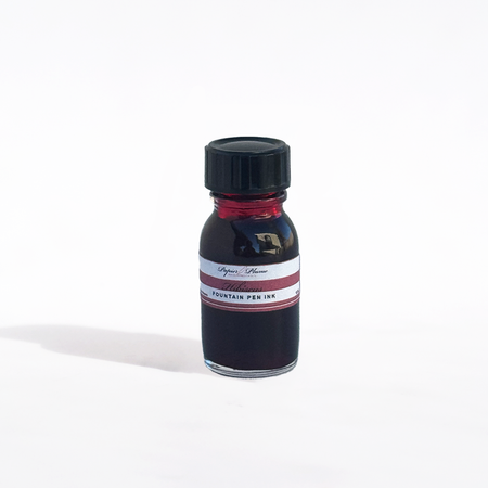Papier Plume fountain pen ink bottle with hibiscus-colored ink in a clear glass container.