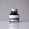 Bottle of Papier Plume Javalina Fountain Pen Ink in a glass container with a black cap and label, showcasing vibrant ink inside.