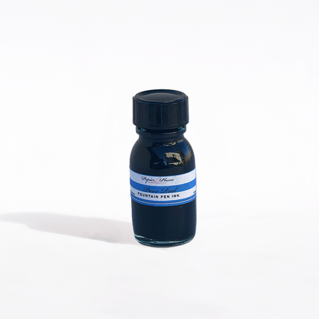 Papier Plume Pavo Real fountain pen ink bottle with vibrant blue and green ink in a clear glass container.