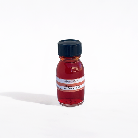 Papier Plume Plaquemines fountain pen ink bottle with vibrant blue ink inside, ready for writing or calligraphy.