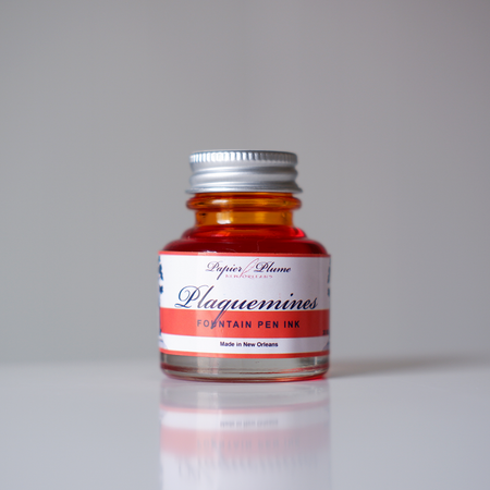 Papier Plume Plaquemines fountain pen ink bottle with vibrant ink inside, designed for elegant writing and calligraphy.