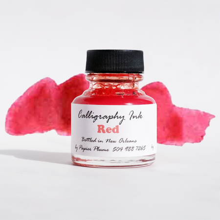 Red bottled calligraphy ink by Papier Plume, showcasing a glass bottle with vibrant red ink inside for artistic calligraphy.