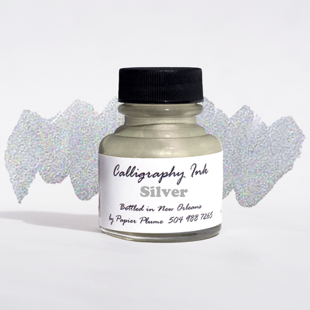 Bottled metallic silver calligraphy ink by Papier Plume with a sleek silver ink bottle and calligraphy nibs on a white background.