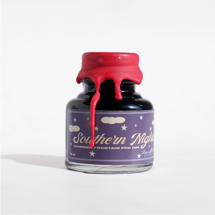 Papier Plume Southern Nights shimmer fountain pen ink bottle with dark blue and gold accents, showcasing elegant ink packaging.