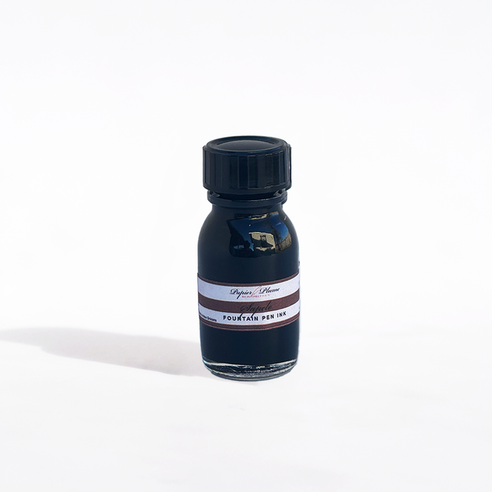 Papier Plume fountain pen ink in Sapele color, featuring a glass bottle with dark amber liquid ink and a black cap.