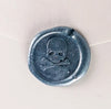 Brass wax seal with skull and bones symbol from Papier Plume, featuring intricate design on a wax seal stamp.