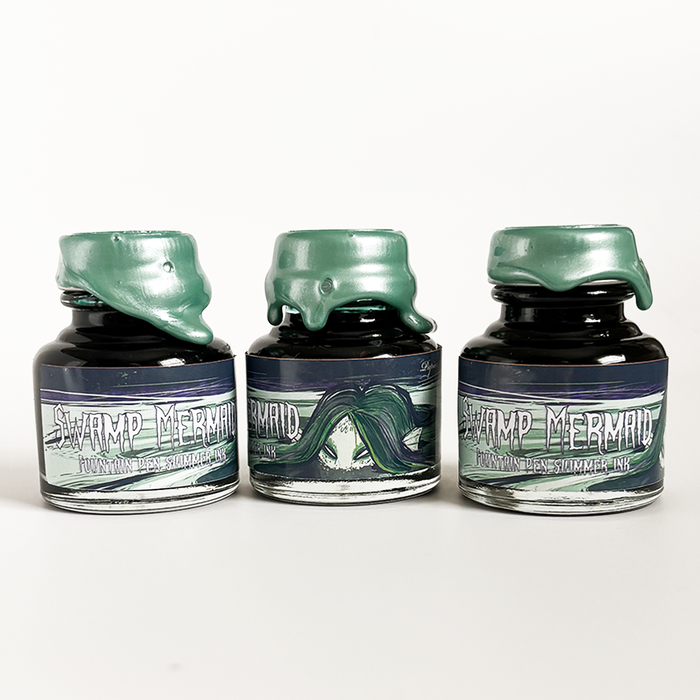 Papier Plume Swamp Mermaid shimmer fountain pen ink bottle with vibrant green and blue hues, ideal for calligraphy and writing.