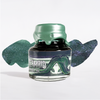 Papier Plume Swamp Mermaid shimmer fountain pen ink in a glass bottle with vibrant green and teal hues and intricate label design.