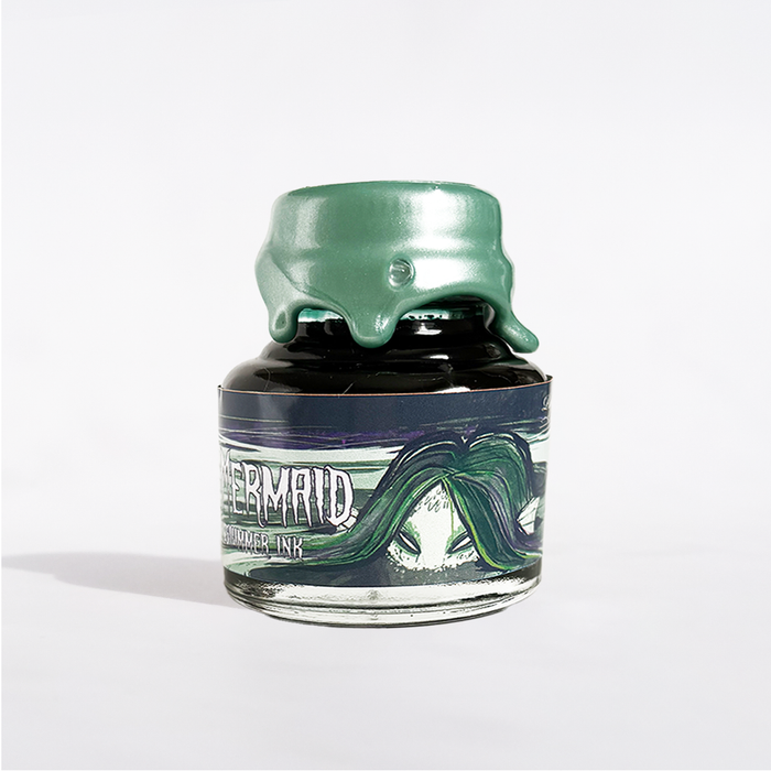 Papier Plume Swamp Mermaid shimmer fountain pen ink in a glass bottle, showcasing vibrant green and shimmering accents.