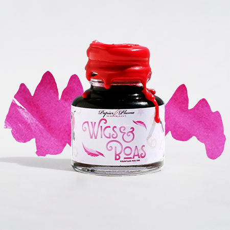 Image of Papier Plume New Orleans Collection fountain pen ink bottle with colorful wig and boa accessories in the background.