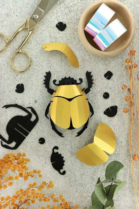 Colorful rainbow paper scarab beetle craft made from paper and plume, created by Assembli for artistic and decorative projects.