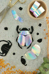 Colorful rainbow paper scarab beetle craft made from folded paper by Assembli, showcasing vibrant, intricate design.