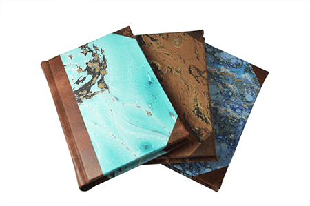 Dark green handcrafted leather journal with marbled paper pages and old-world spine, featuring a lined interior by Il Cartiglio.