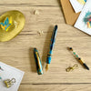Esterbrook x BUNGUBOX Kingfisher Limited Edition Estie fountain pen with vibrant blue and gold accents, resting on a white background.